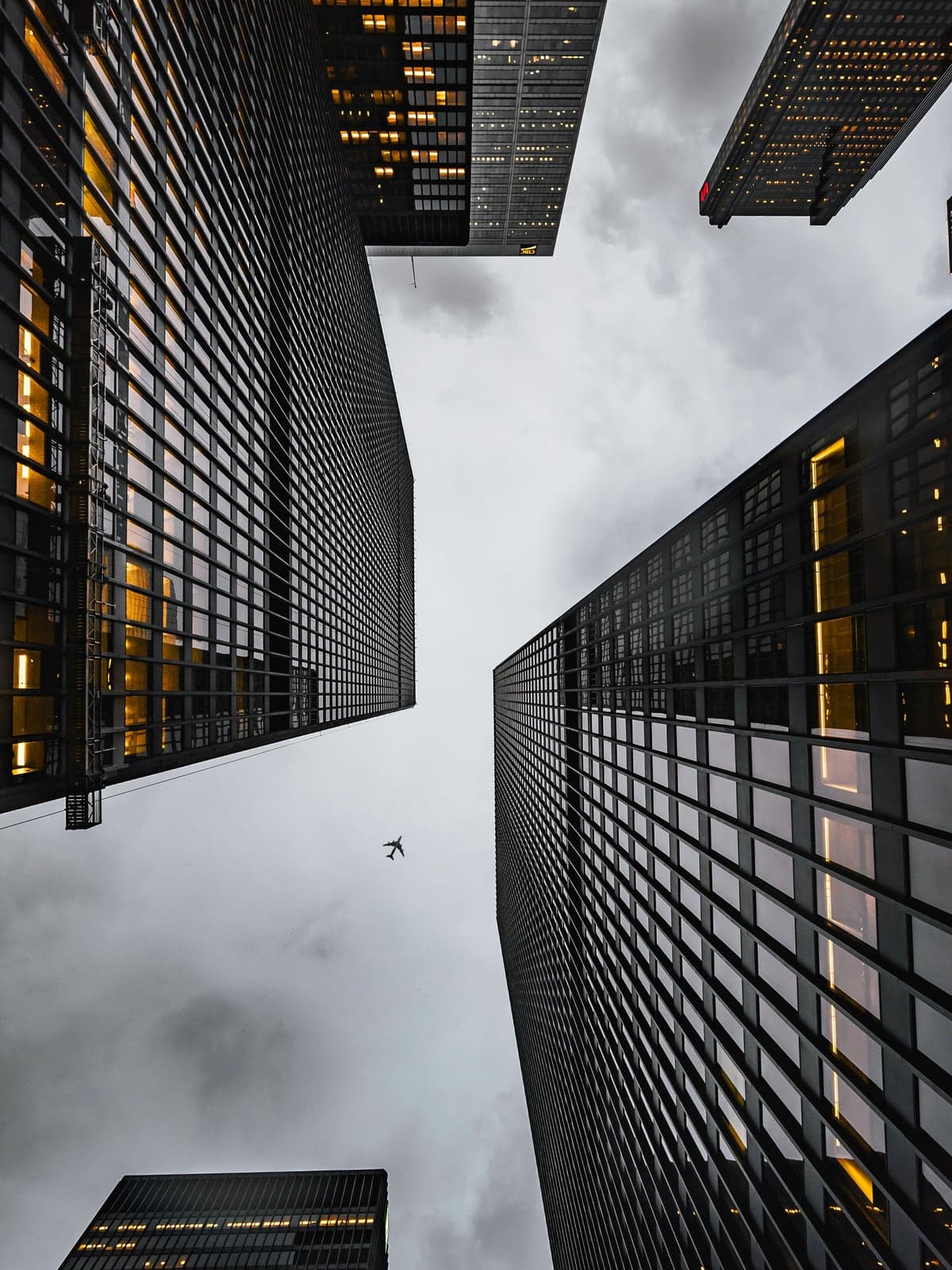 Commercial office towers seen from street level, upper floors lit from within at dusk
